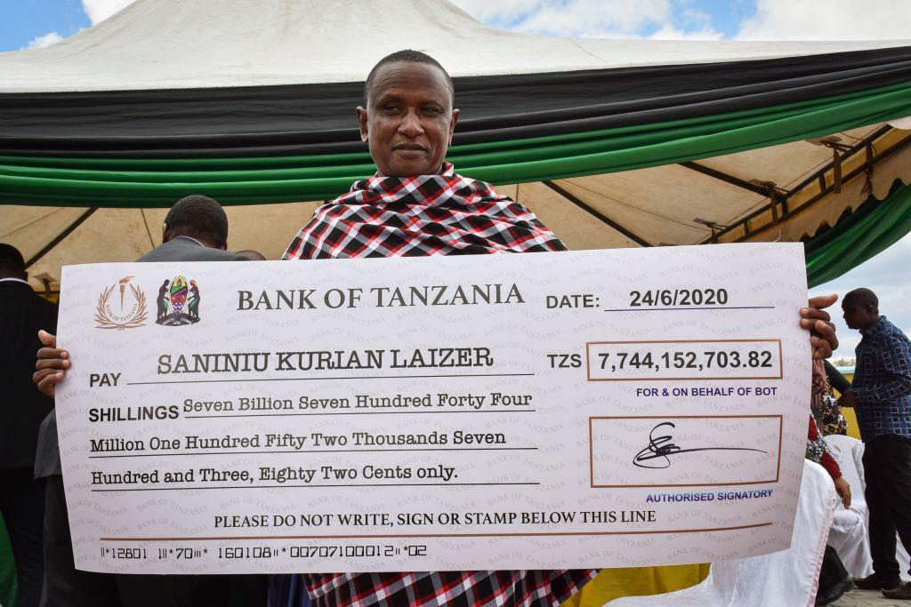 Laizer poses with his enlarged check copy from the government after selling his first two gemstones in Manyara on June 24, 2020. (FILBERT RWEYEMAMU/AFP via Getty Images)