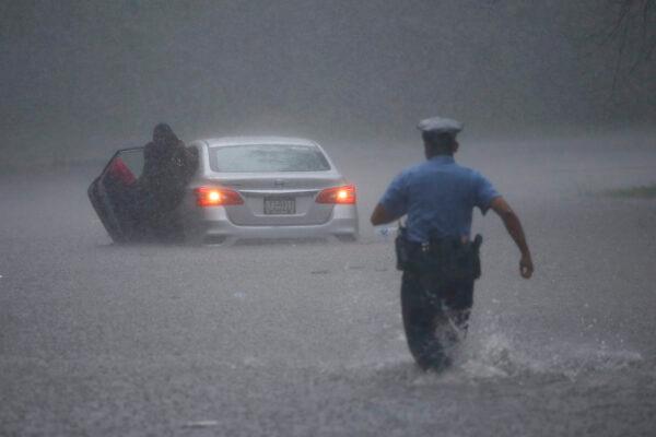 A Philadelphia police officer rushes to help a stranded motorist during Tropical Storm Isaias on Aug. 4, 2020, in Philadelphia. (AP Photo/Matt Slocum)