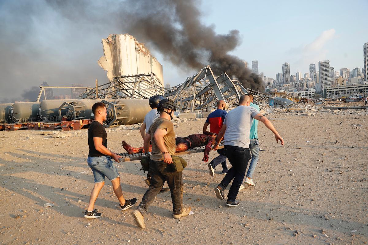 Civilians carry a victim at the explosion scene that hit the seaport, in Beirut Lebanon, on Aug. 4, 2020. (Hussein Malla/AP Photo)