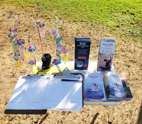 A table with Falun Gong pamphlets, lotus charms, and petition forms at Mitchell Park in Palo Alto, Calif., on Aug. 1, 2020. (David Lam/The Epoch Times)