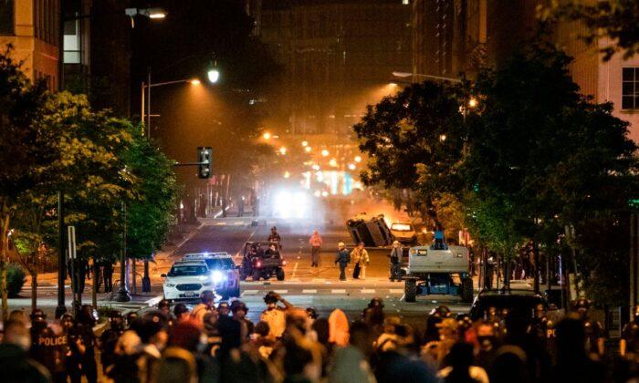 One car is flipped over while another one burns as protestors and police face off near the White House protesting the death of George Floyd at the hands of Minneapolis Police in Washington, on May 31, 2020. (Samuel Corum/AFP via Getty Images)