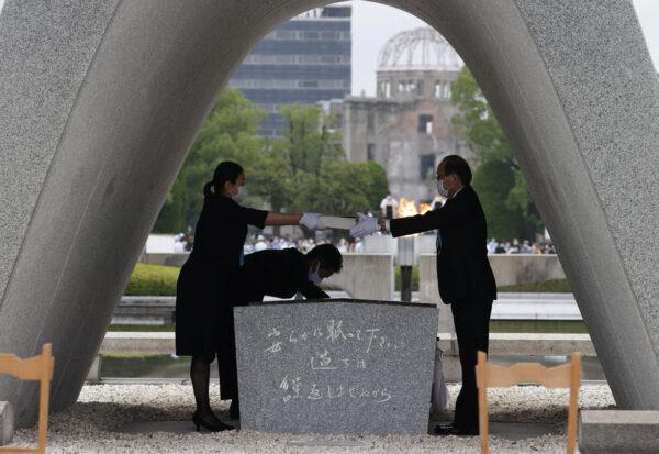 The name list of war dead is given to Hiroshima City mayor Kazumi Matsui from a representative of bereaved families of the 1945 atomic bombing victims at Peace Memorial Park in Hiroshima, western Japan on Aug. 6, 2020, on the 75th anniversary of the atomic bombing of the city. (Kyodo/via Reuters)