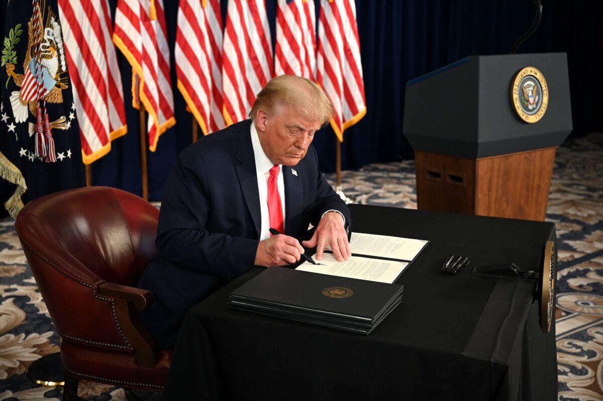 President Donald Trump signs executive orders extending coronavirus economic relief, during a news conference in Bedminster, N.J., on Aug. 8, 2020. (Jim Watson/AFP via Getty Images)