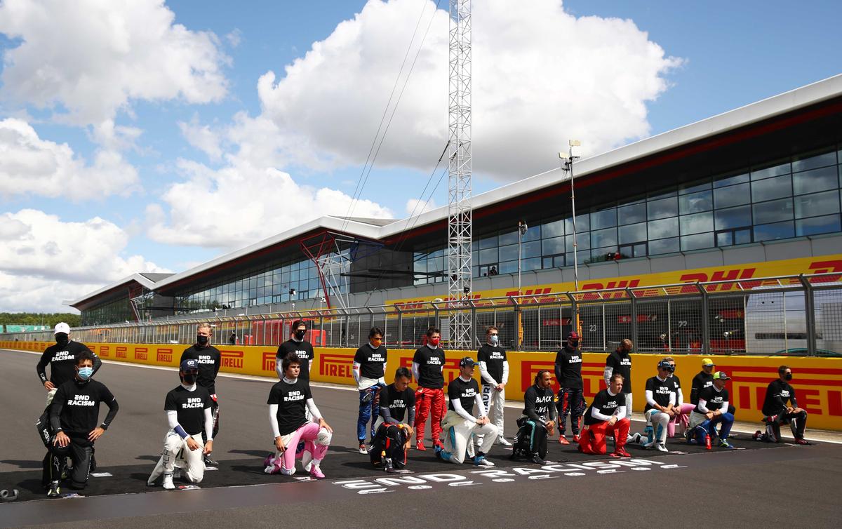 Drivers stand and kneel on the grid before the race. (Reuters)