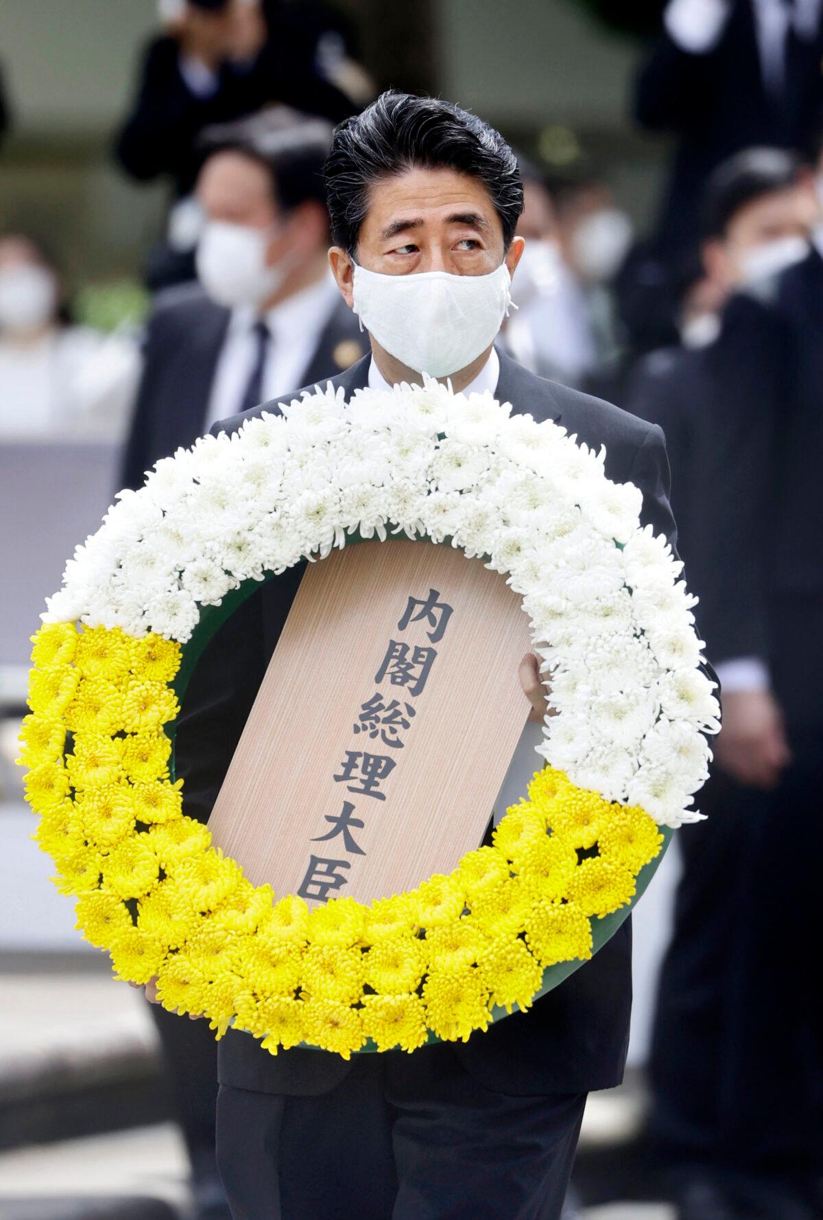 Japanese Prime Minister Shinzo Abe carries the wreath to offer during a ceremony to mark the 75th anniversary of the U.S. atomic bombing at the Peace Park in Nagasaki, southern Japan, on Aug. 9, 2020. (Kyodo News via AP)