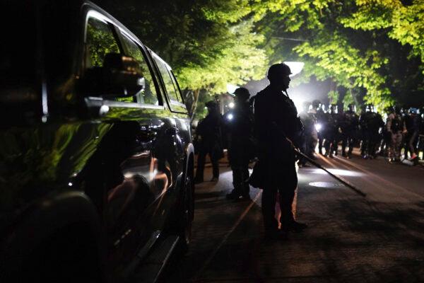 Portland police officers walk through the Laurelhurst neighborhood after dispersing a protest of about 200 people from in front of the Multnomah County Sheriff's Office in Portland, Ore., early in the morning on Aug. 8, 2020. (Nathan Howard/AP Photo)