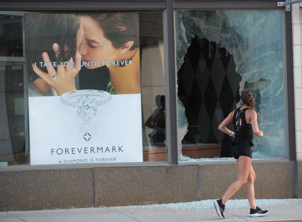 A jogger runs past a broken storefront window after parts of the city had widespread looting and vandalism, in Chicago on Aug. 10, 2020. (Scott Olson/Getty Images)
