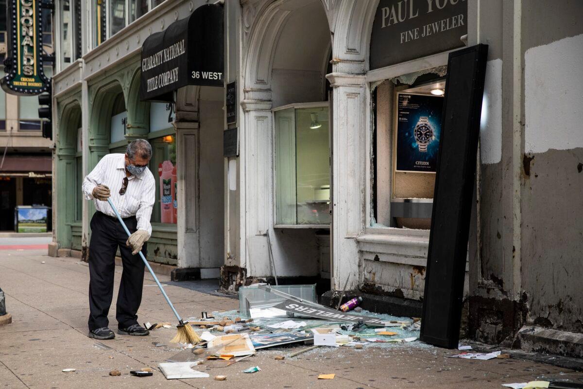 A man sweeps up outside Paul Young Fine Jewelers after looting broke out in the Loop and surrounding neighborhoods overnight in Chicago, Aug. 10, 2020. (Ashlee Rezin Garcia /Chicago Sun-Times via AP)
