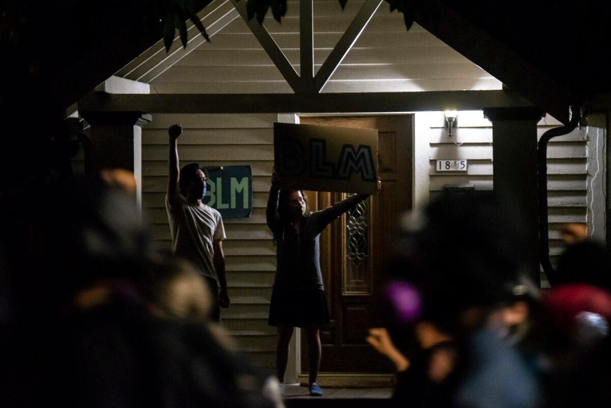 Portland residents hold signs as demonstrators move by their home during unrest in Portland, Ore., on Aug. 10, 2020. (Nathan Howard/Getty Images)
