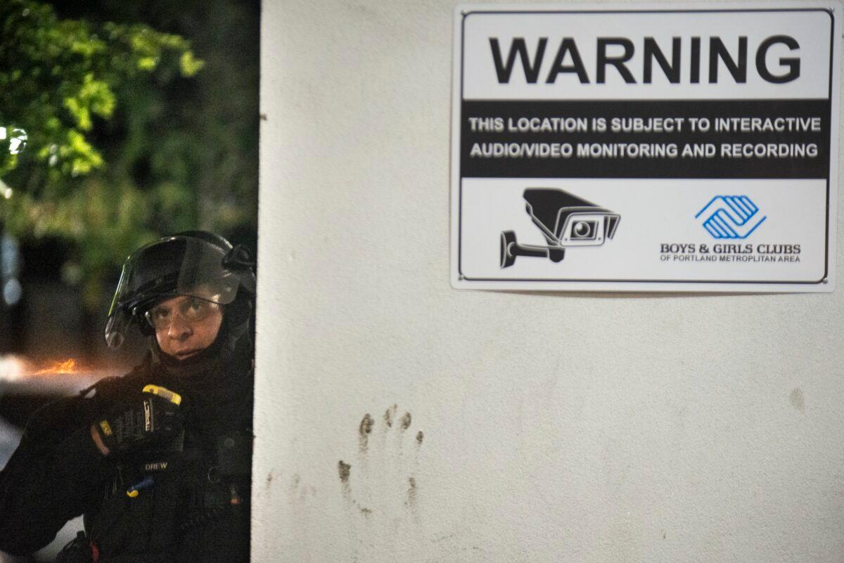 An Oregon State Trooper watches the crowd from behind a concrete wall near the Portland Police Bureau's North Precinct in Portland, Ore., on Aug. 11, 2020. (Nathan Howard/Getty Images)