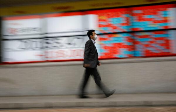 A man wearing a protective mask walks in front of a stock quotation board outside a brokerage in Tokyo on May 18, 2020. (Kim Kyung-Hoon/File Photo/Reuters)