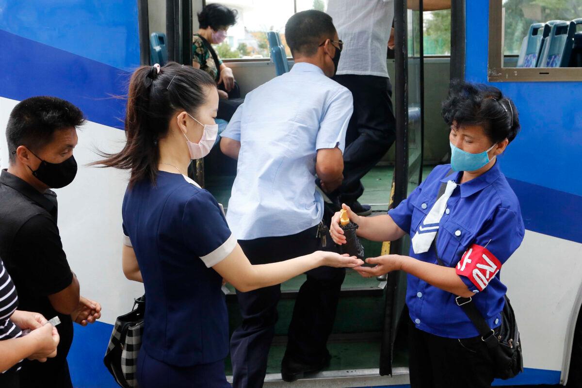 A passenger wearing a face mask to help curb the spread of the coronavirus is disinfected her hand before getting on a trolley bus in Pyongyang, North Korea, on Aug. 13, 2020. (Jon Chol Jin/AP Photo)