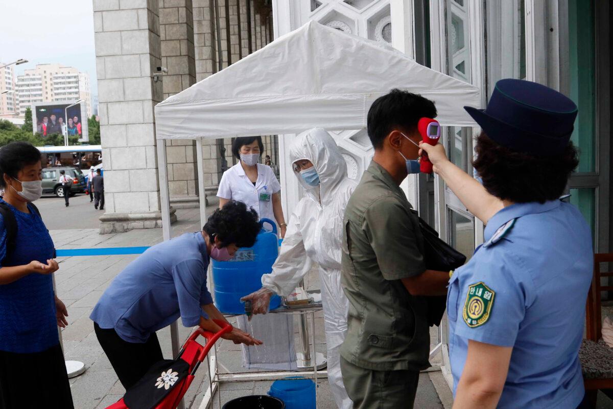 People are disinfected their hands and get fever checked before going into the Pyongyang Railway Station in Pyongyang, North Korea, on Aug. 13, 2020. (Cha Song Ho/AP Photo)
