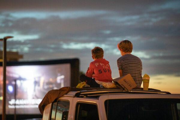 Children watch a movie from the top of a car in Newport Beach, Calif., on Aug. 13, 2020. (John Fredricks/The Epoch Times)