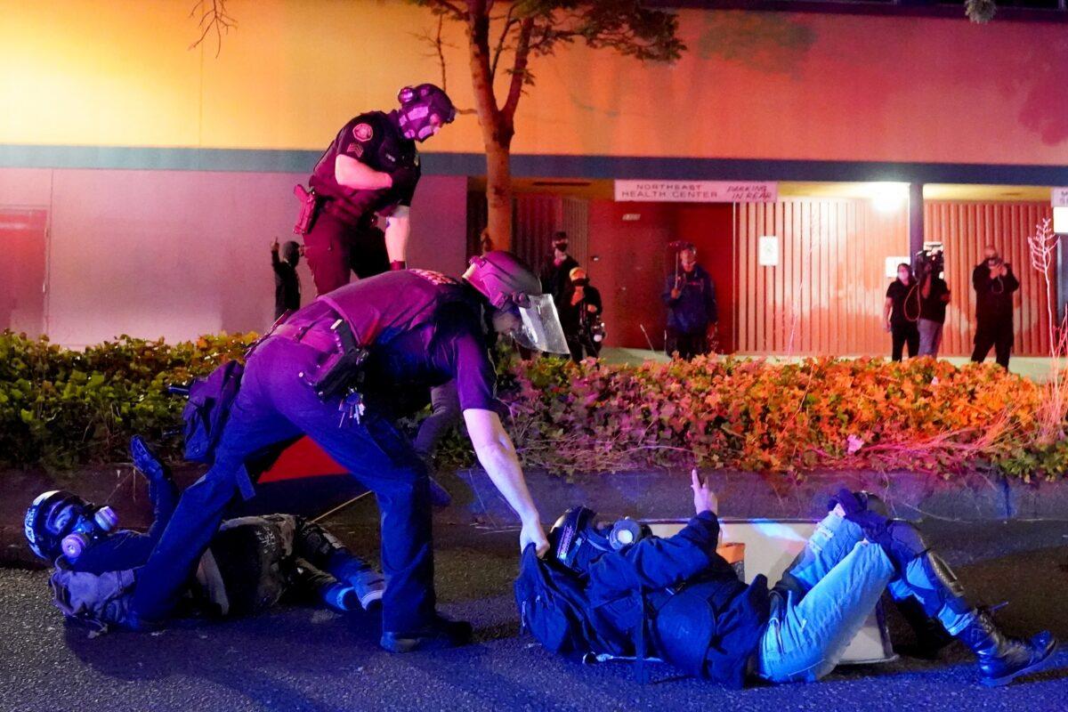 Portland police and Oregon State Patrol troopers work together to arrest two people in front of the Portland Police Bureau's North Precinct during continued rioting in Portland, Ore., on Aug. 11, 2020. (Nathan Howard/Getty Images)