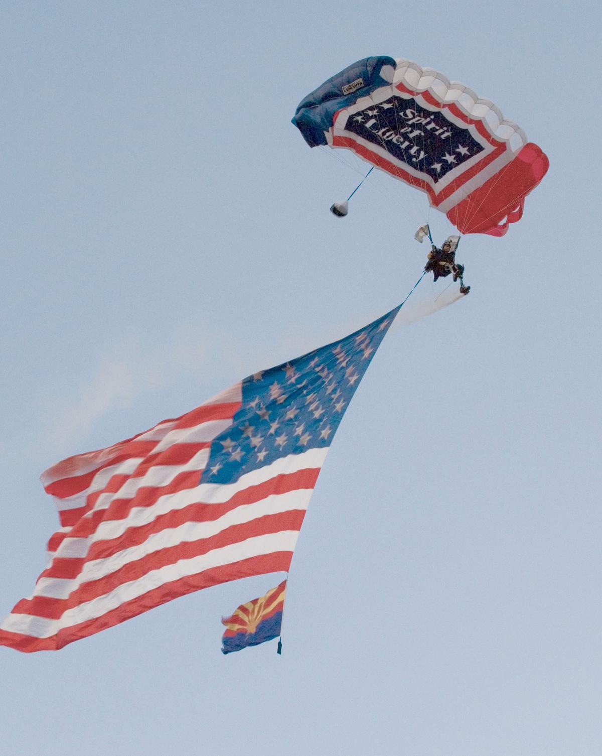 Bowman parachutes from a helicopter while waving a giant American flag during the Fourth of July Freedom Fest at the Fairmont Scottsdale Princess Resort on July 3. (<a href="https://www.dvidshub.net/image/620138/tears-freedom">Spc. Danielle Gregory</a>)