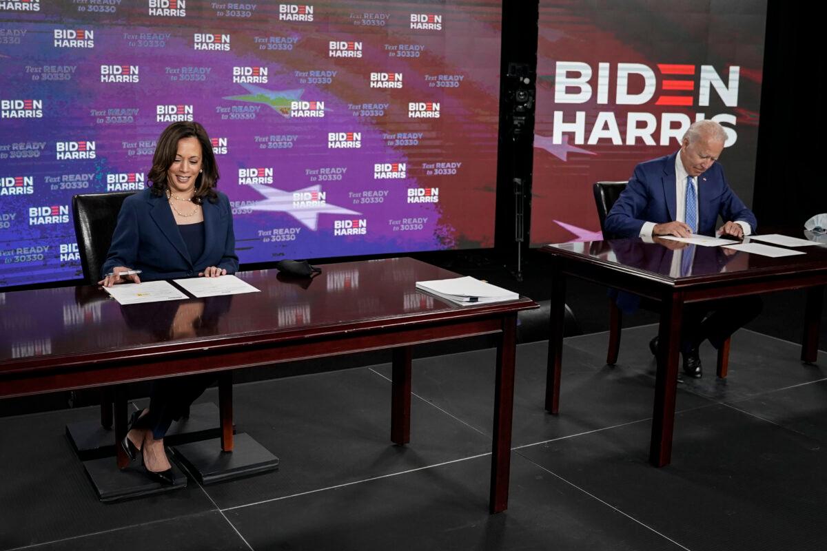 Presumptive Democratic presidential nominee Joe Biden, right, and Sen. Kamala Harris (D-Calif.) sign papers at the Hotel DuPont in Wilmington, Del., on Aug. 14, 2020. (Drew Angerer/Getty Images)