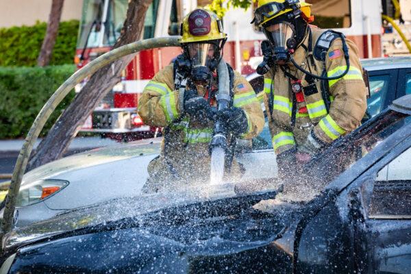 Orange County firefighters use a hose to spray water on a burning Mercedes-Benz in Irvine, Calif., on Aug. 17, 2020. (John Fredricks/The Epoch Times)