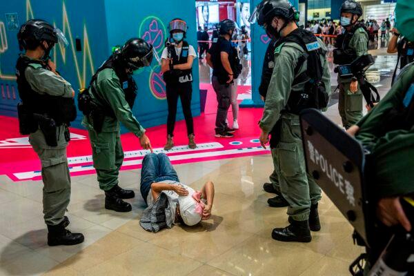 A riot police officer (2L) points at a woman (C) laying down after being searched during a demonstration in a mall in Hong Kong on July 6, 2020. (Isaac Lawrence/AFP via Getty Images)