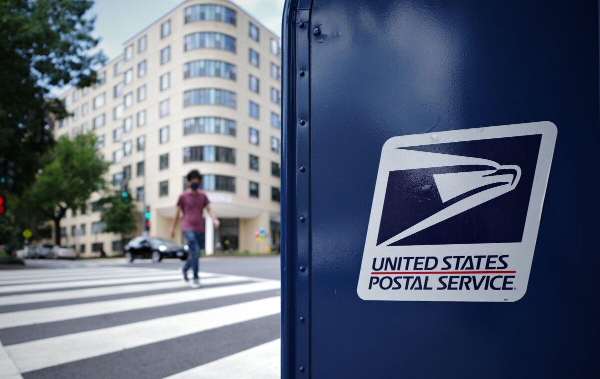 A man crosses an intersection next to a U.S. Postal Service mailbox in Washington on Aug. 17, 2020. (Mandel Ngan/AFP via Getty Images)
