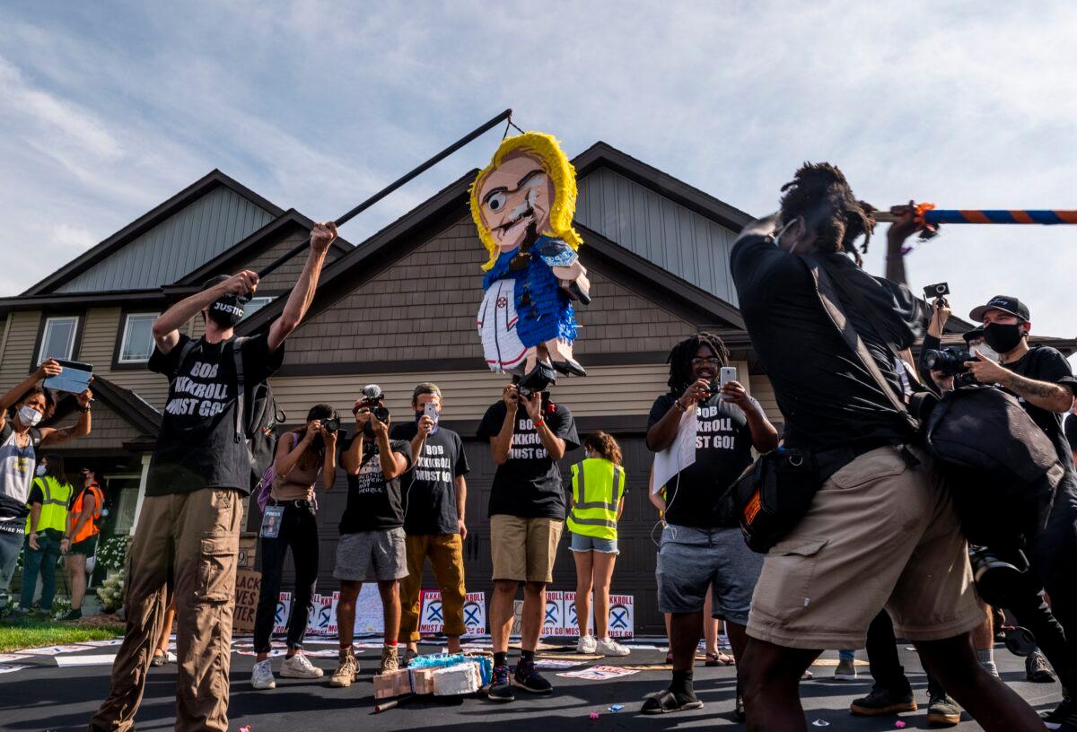 People bash pinatas made in the likeness of Minneapolis police union head Bob Kroll and WCCO reporter Liz Collin, outside their home in Hugo, Minn., on Aug. 15, 2020. (Stephen Maturen/Getty Images)