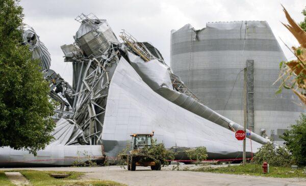 Iowa Department of Transportation workers help with tree debris removal as grain bins from the Archer Daniels Midland facility are seen severely damaged in Keystone, Iowa, on Aug. 12, 2020. (Jim Slosiarek/The Gazette via AP)