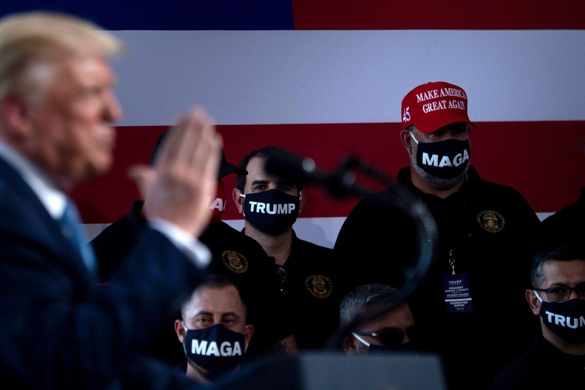 A man wears a "Make America Great Again" hat as he and others listen to President Donald Trump during a rally at Yuma International Airport in Yuma, Ariz., on Aug. 18, 2020. (Brendan Smialowski/AFP via Getty Images)