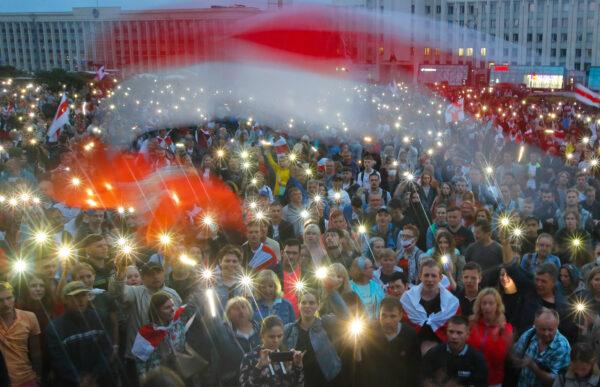 Belarusian opposition supporters light phones lights and wave an old Belarusian national flags during a protest rally in front of the government building at Independent Square in Minsk on Aug. 19, 2020. (Dmitri Lovetsky/AP Photo)