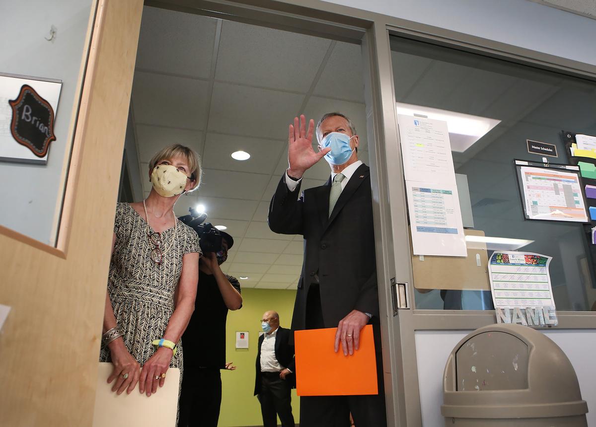 Massachusetts Gov. Charlie Baker and Secretary of Health and Human Services Marylou Sudders wave to students from a classroom door at The New England Center for Children in Southborough, Mass., on July 13, 2020. (Nancy Lane/Pool/AFP via Getty Images)