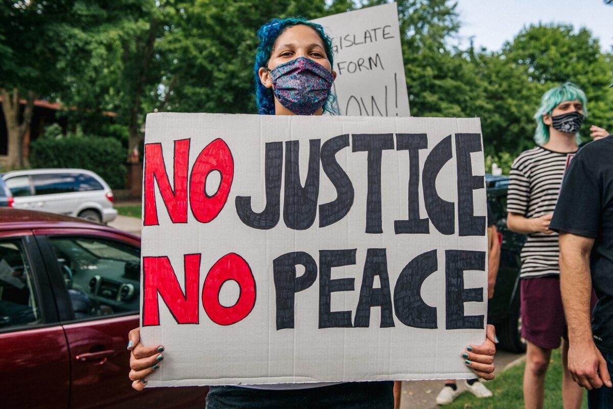 A woman stands with a sign that reads "No Justice No Peace" during a demonstration in St. Paul, Minn., on June 24, 2020. (Brandon Bell/Getty Images)