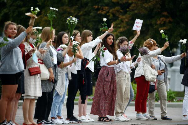 Women hold flowers while lining up during a demonstration against violence in Minsk on Aug. 20, 2020. (Vasily Fedosenko/Reuters)