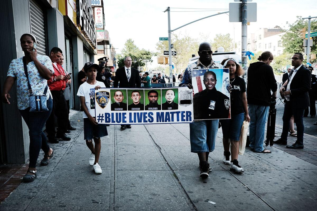 Cameron Hunt stands with his father Calvin holding a Blue Lives Matter banner outside of a Bronx church during the funeral for NYPD Officer Miosotis Familia, who was shot and killed in what police have called "an unprovoked attack" in the Bronx in New York City on July 11, 2017. (Spencer Platt/Getty Images)