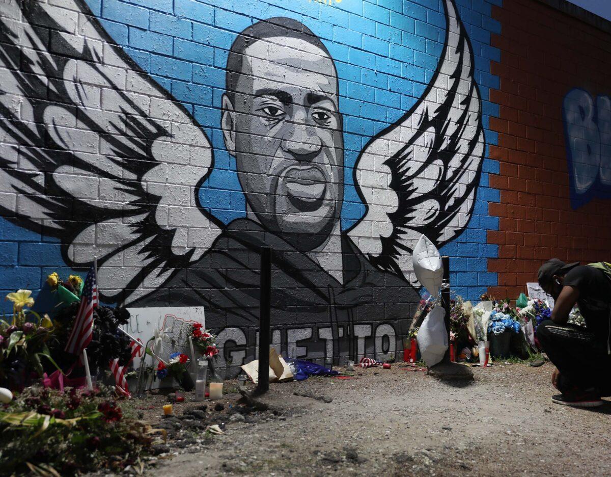 Joshua Broussard kneels in front of a memorial and mural that honors George Floyd at the Scott Food Mart corner store in Houston's Third Ward, where Mr. Floyd grew up in Houston, Texas, on June 8, 2020. (Joe Raedle/Getty Images)