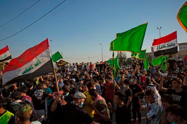 Iraqis lift national flags as they demonstrate near the governor's residence in the southern city of Basra, to protest assassinations and demand the resignation of top security officials, on Aug. 16, 2020. (Hussein Faleh/AFP via Getty Images)