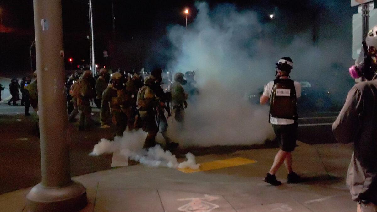 A member of the media stands amid tear gas used by police officers to clear rioters near an Immigration and Customs Enforcement centre in Portland, Ore., Aug. 19, 2020, in this still image from a video obtained from social media. (Twitter/DAVE_BLAZER /Instagram/AARON2543/via Reuters