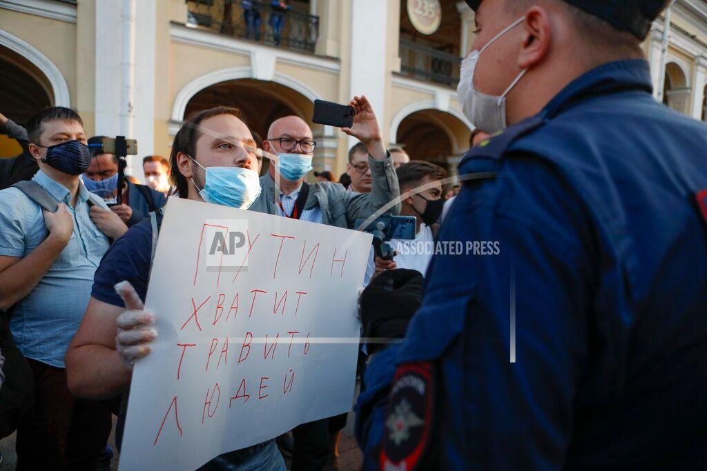 A protester stands in front of a police officer holding a poster reading "Putin stop poisoning people!" during a picket in support of Russian opposition leader Alexei Navalny in the center of St. Petersburg, Russia, on Aug. 20, 2020. (Elena Ignatyeva/ AP Photo)