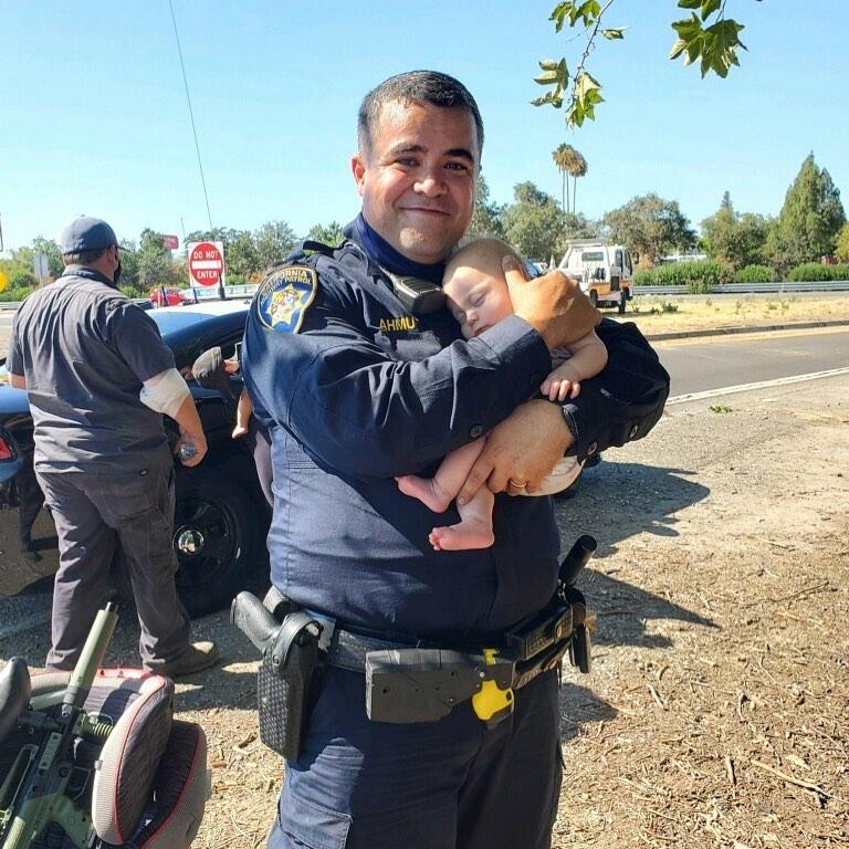 Officer Matthew Ahmu from California Highway Patrol Office holding an infant after a collision. (Courtesy of <a href="https://www.facebook.com/CHPNorthsac/">CHP – North Sacramento</a>)