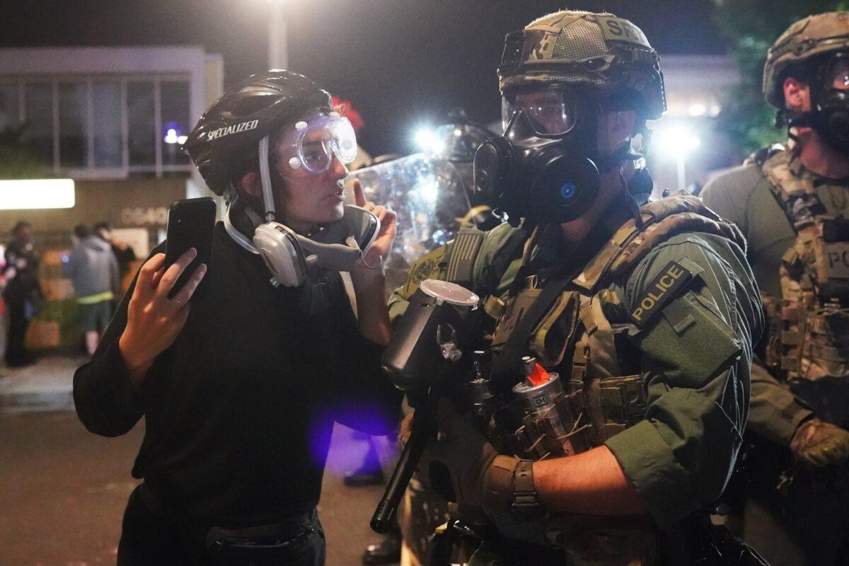 A man speaks with a federal officer during a riot outside the Immigration and Customs Enforcement detention facility in Portland, Ore., early Aug. 21, 2020. (Nathan Howard/Getty Images)