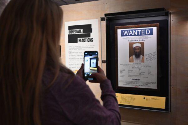 A woman takes a picture of an Osama bin Laden wanted poster at an exhibition at the National 9/11 Memorial Museum in New York City on Nov. 7, 2019. (Angela Weiss/AFP via Getty Images)