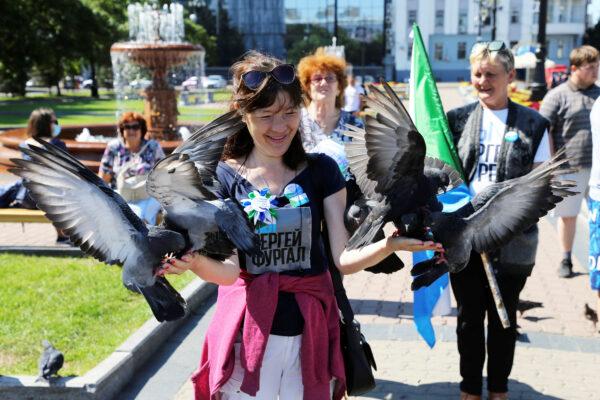 A participant feeds pigeon during an anti-Kremlin rally in support of former regional governor Sergei Furgal arrested on murder charges in the far eastern city of Khabarovsk, Russia, on Aug. 22, 2020. (Evgenii Pereverzev/Reuters)