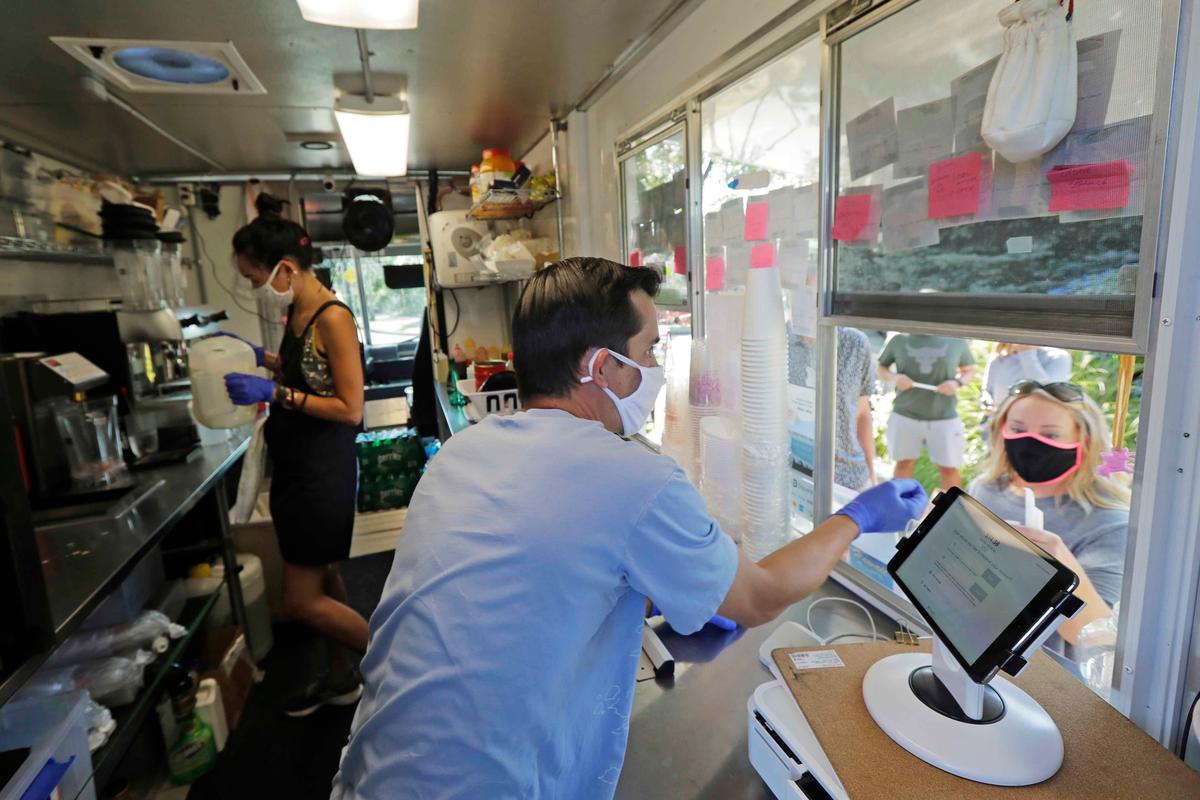 Athan Freitas, center, and Kaye Fan, left, make drinks and take orders in their Dreamy Drinks food truck, Monday, Aug. 10, 2020, near the suburb of Lynnwood, Wash., north of Seattle. (Ted S. Warren/AP)