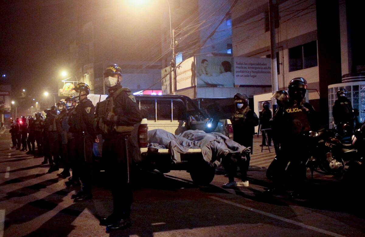 Police officers stand guard near two bodies outside of a disco in Lima, Peru, on Aug. 23, 2020. (Diego Vertiz via AP Photo)