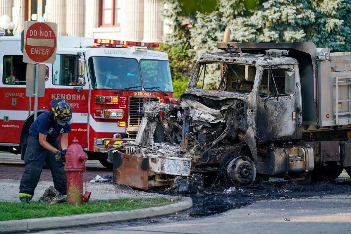 A firefighter is seen near a burnt out truck near the Kenosha County Courthouse in Kenosha, Wis., on Aug. 24, 2020. (Morry Gash/AP Photo)