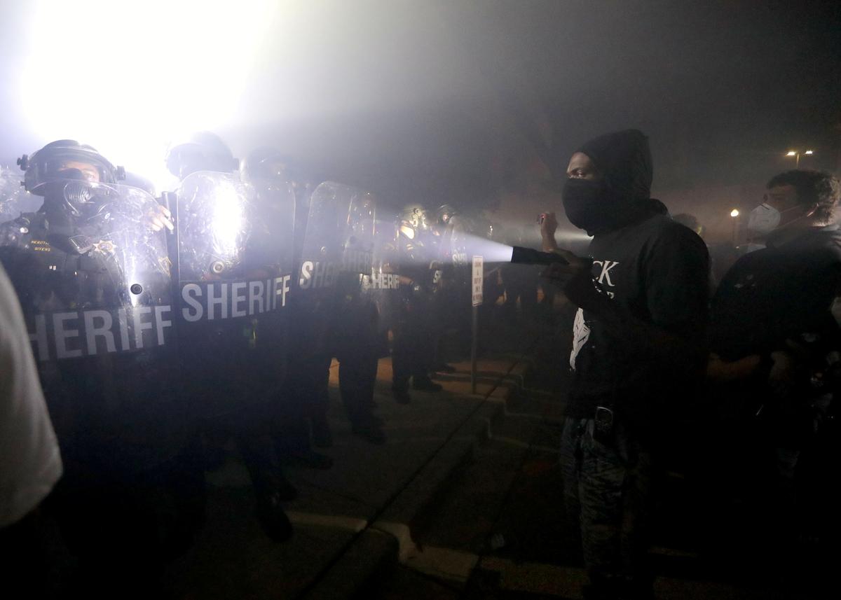 A protestor shines a flashlight in the direction of Kenosha County Sheriffs Deputies outside the Kenosha Police Department in Kenosha, Wis., on Aug. 23, 2020. (Mike De Sisti/Milwaukee Journal Sentinel via USA TODAY via Reuters)