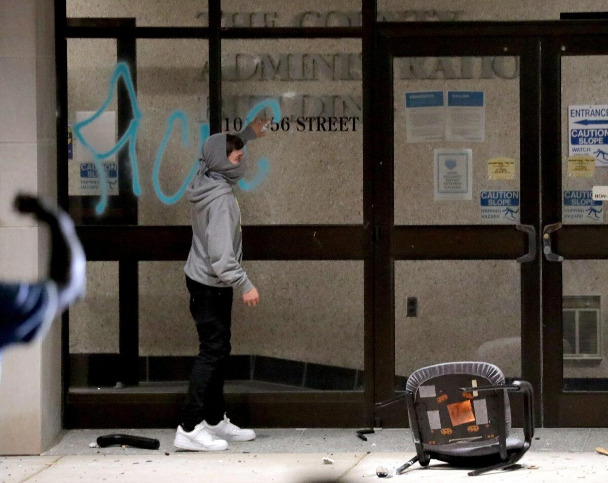 A window is spraypainted at the Kenosha County Administration building next to the Kenosha County Courthouse in Kenosha, Wis., during unrest following the police shooting of Jacob Blake on Aug. 23, 2020. (Mike De Sisti/Milwaukee Journal Sentinel via USA TODAY via Reuters)