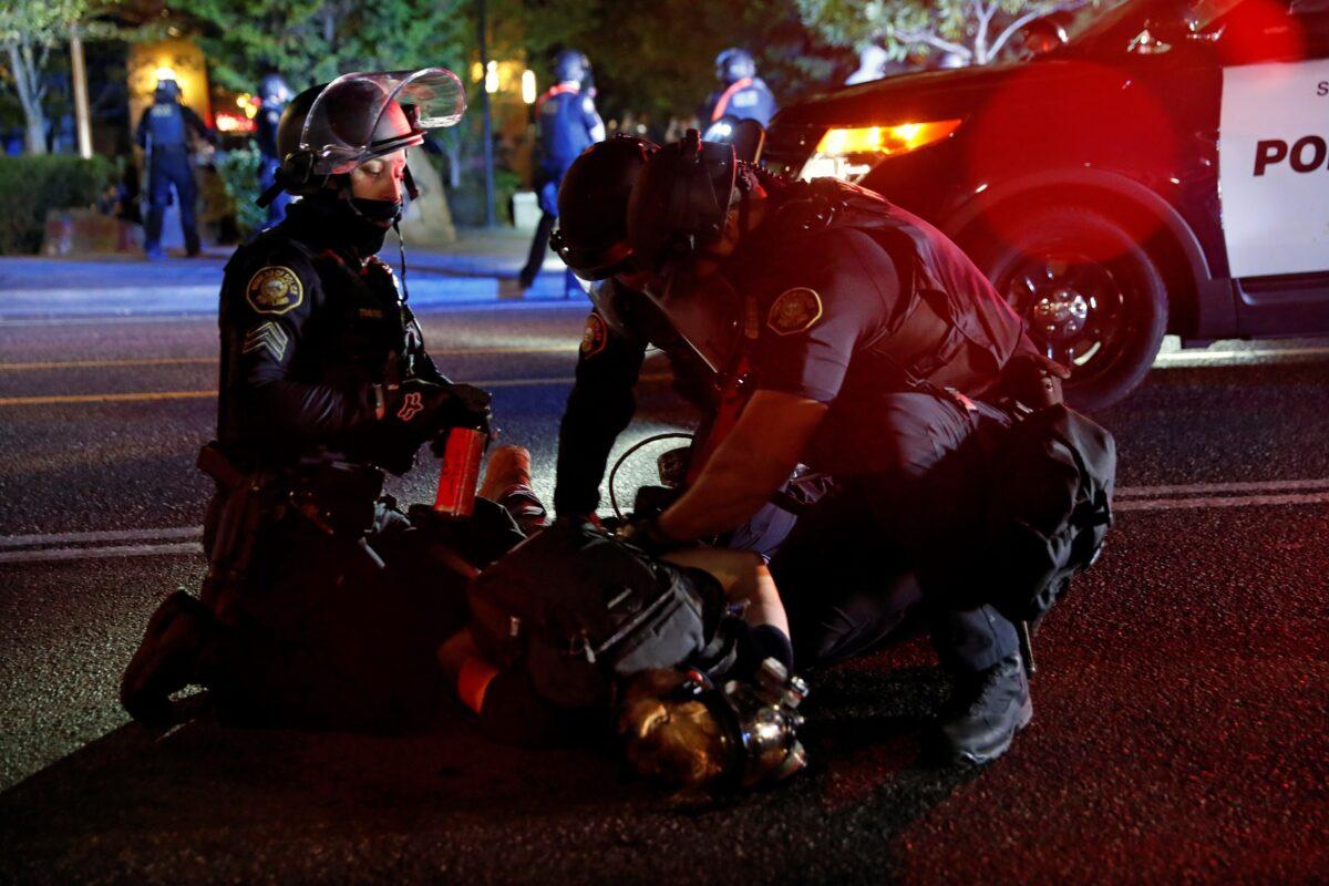 Police officers detain a person during a riot in Portland, Ore., Aug. 24, 2020. (Terray Sylvester/Reuters)