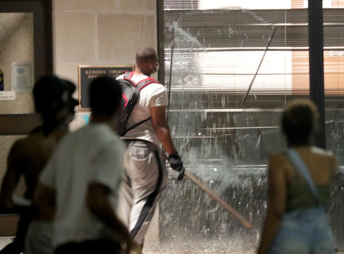 Rioters smash windows at the Kenosha County Administration Building during unrest following the police shooting of Jacob Blake in Kenosha, Wis., on Aug. 23, 2020. (Mike De Sisti/Milwaukee Journal Sentinel via USA TODAY via Reuters)