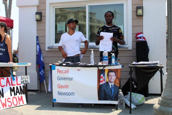 A booth calling for the recall of Gov. Gavin Newsom is set up near a protest against human trafficking in Huntington Beach, Calif., on Aug. 22, 2020. (Jamie Joseph/The Epoch Times)