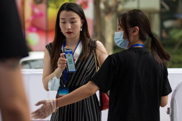 A staff worker wears a protective masks while checking a woman's health QR code by the entrance prior to an outdoor screening event in Shanghai, China, on July 25, 2020. (Yifan Ding/Getty Images)