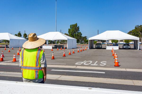 A worker waits to guide vehicles at a new COVID-19 testing super site in Costa Mesa, Calif., on Aug. 26, 2020. (John Fredricks/The Epoch Times)